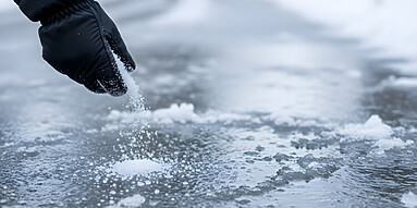 hand salting icy sidewalk